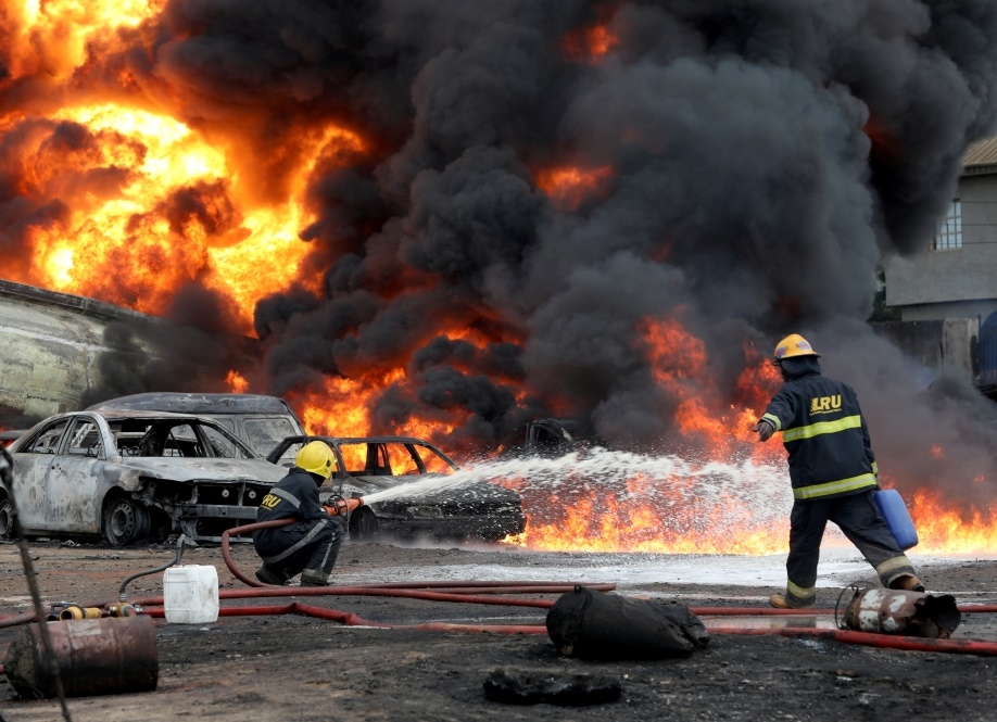 A fireman targets his water hose at the base of a fire after a pipeline fire erupted in Ijegun area of Lagos